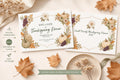 Two white invitations with autumn leaves, pumpkins, and grapes, one with event details and the other with "Smith Family Thanksgiving Dinner 2027", next to a brown envelope and dried flowers.