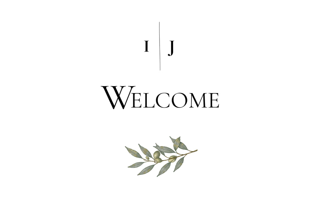 A white sign with black text reading "I J" separated by a vertical line, and below that, "WELCOME" with a green olive branch illustration underneath.