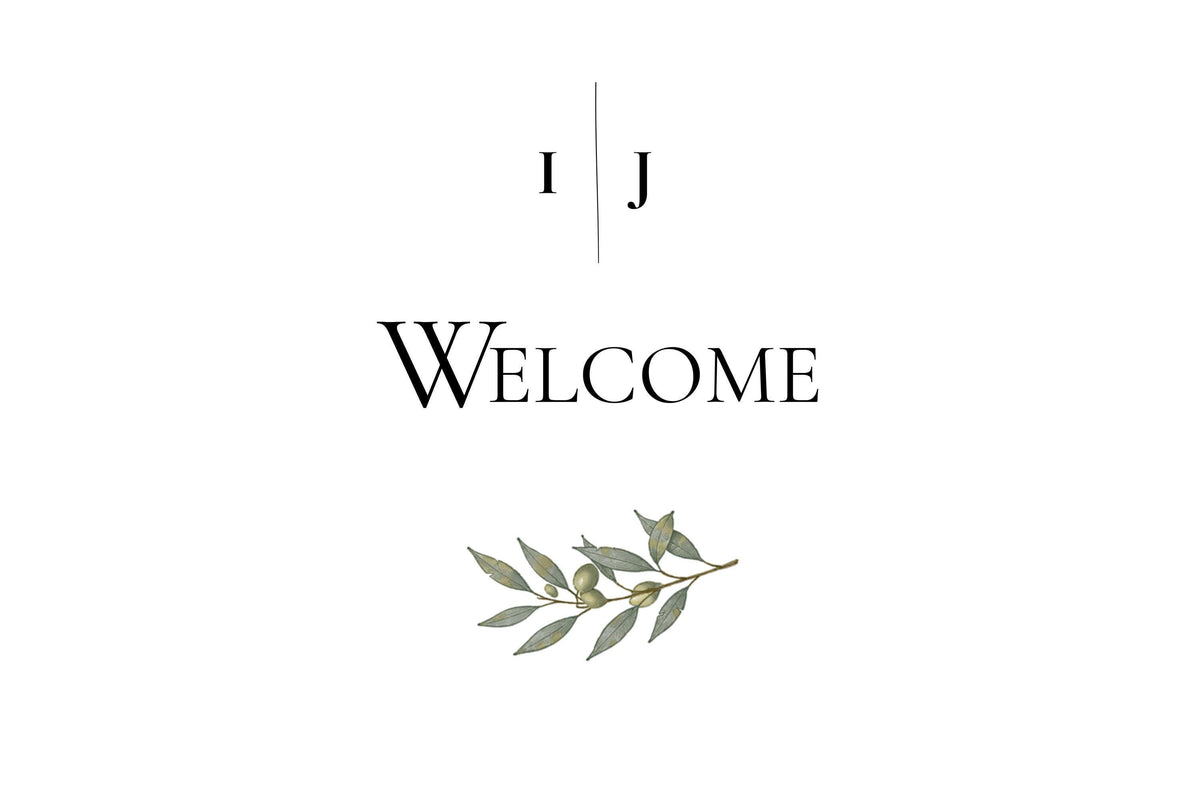 A white sign with black text reading "I J" separated by a vertical line, and below that, "WELCOME" with a green olive branch illustration underneath.