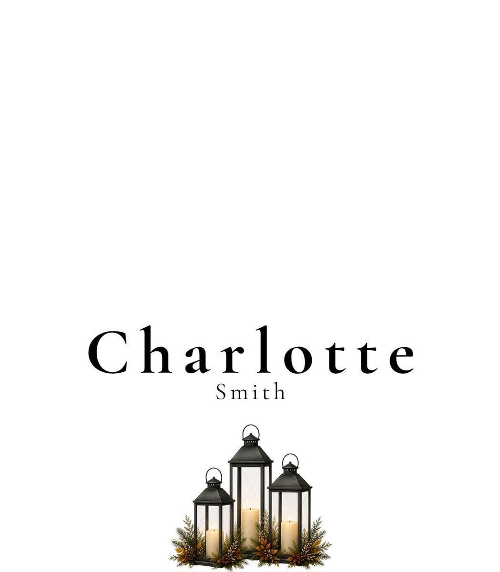 A white place card with the name "Charlotte Smith" in black text, with three black lanterns with candles and green and brown foliage at the bottom center.