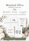 A flat lay of five white wedding signs with olive branch accents, including "Guest Book," "Photo Booth," "Cards & Gifts," "Signature Drinks," and "Table 01," surrounded by white roses and a candle.
