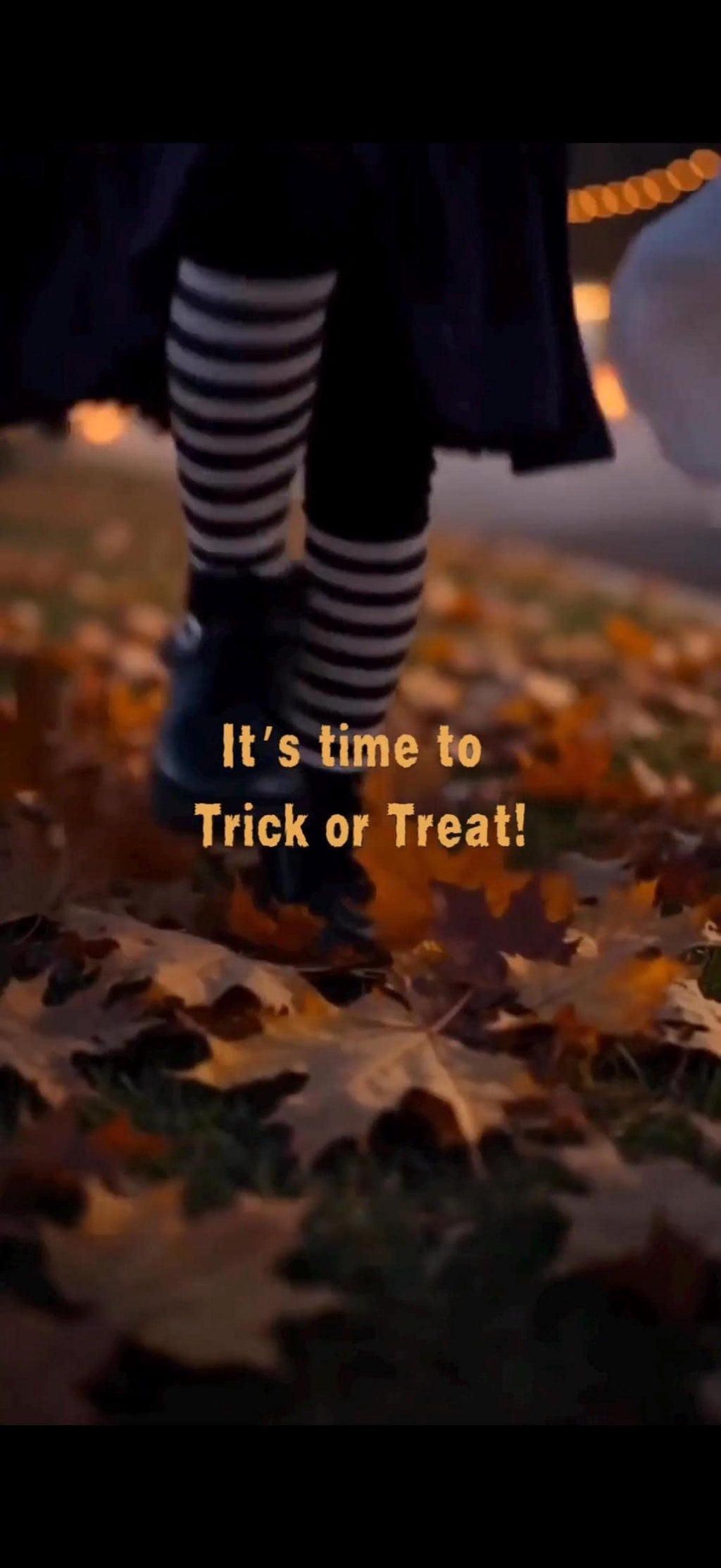A person wearing black and white striped stockings and black shoes walks on a path covered with autumn leaves, with text "It's time to Trick or Treat!" superimposed.